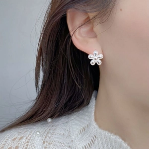 Close-up of S925 sterling silver flower stud earrings with milgrain edges on ear