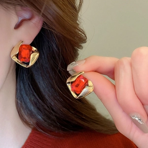 Close-up of vintage gold earrings with square red stones worn by a model