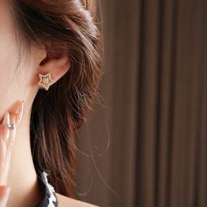 Close-up of star-shaped gold stud earring with sparkling cubic zirconia on model's ear