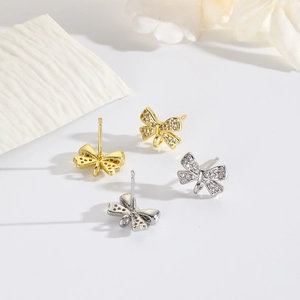 Close-up of bow knot stud earrings with cubic zirconia inlay in gold and silver finish