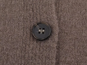 Détail de la texture en maille marron et du bouton en écaille sur un gilet d'hiver élégant