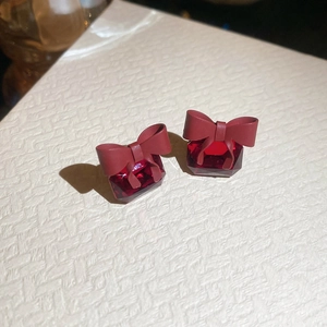 Close-up of red ribbon bow earrings with square red zircon crystal in matte finish