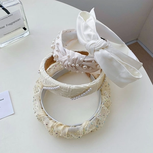 Detailed shot of four cream-colored headbands with silk bows, pearls and sparkling rhinestones