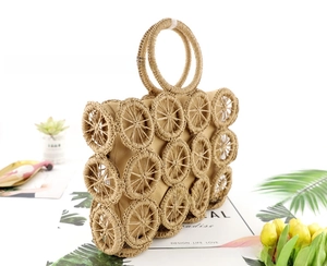 Detail of woven straw handbag featuring circular patterns and round top handles