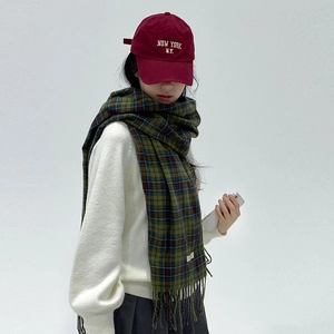 Woman wearing vintage green plaid scarf with tassels and red New York baseball cap