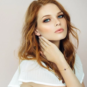 Minimalistisches Goldketten-Armband mit lila Natursteinperle, getragen von einem Modell
