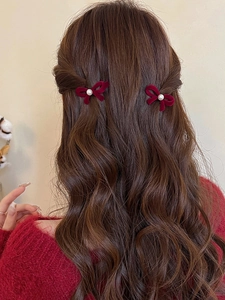 Close-up of red velvet bow hair clips with pearls worn on wavy brown hair