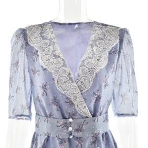 Détail du col en V avec dentelle blanche et motif floral sur robe bleu clair