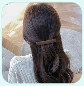 Close-up of a large matte dark brown spring hair clip on long wavy hair back view