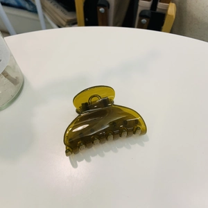 Detail view of a dark green transparent heart-shaped hair claw clip on a white table