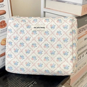 Détail d'une trousse à maquillage en coton matelassé fleuri avec fermeture éclair