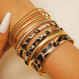 Detailed view of layered leopard print leather bracelets and gold bangles set
