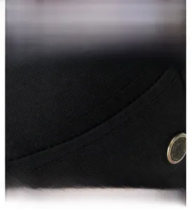 Macro view of sewing craftsmanship and bronze metal rivet on a black flat top cap