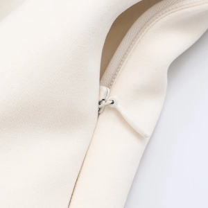 Dettaglio della cerniera invisibile e del tessuto twill su un vestito bianco crema