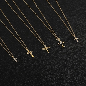 Detailed view of five gold-plated cross necklaces with cubic zirconia on black leather