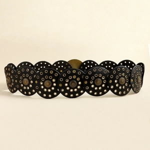 Detail of black leather belt featuring bronze metal studs and circular pattern cutouts