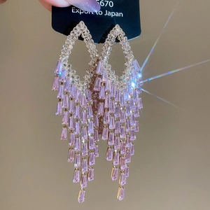 Macro shot of gold-tone tassel earrings featuring sparkling pink rectangular crystals