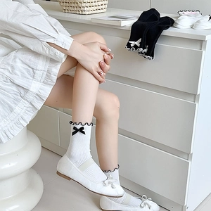 Close-up of white JK socks with black ruffle trim and a delicate bow detail