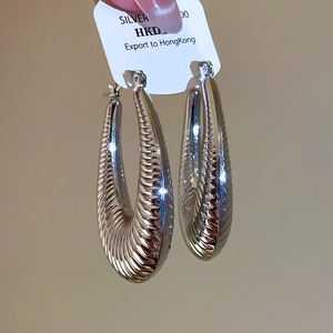 Detailed view of silver oval hoop earrings featuring textured ripple finish and 925 silver pin