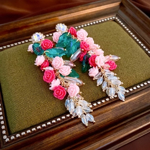 Detail of rose floral earrings with crystal tassels on a green velvet vintage background