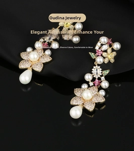 Close-up of gold floral earrings with crystal tassels and teardrop pearls on black silk