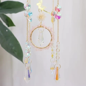 Macro detail of golden sun catcher featuring pink raw crystals and faceted glass prism