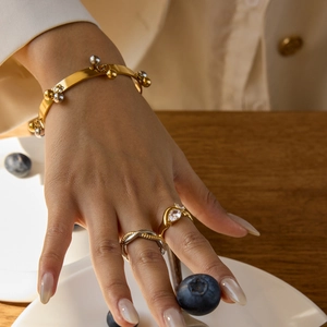 Close-up of gold beaded bracelet and crystal ring worn by model in elegant setting
