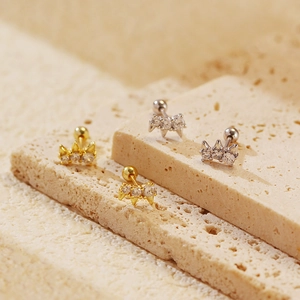 Macro shot of silver and gold geometric rivet earrings with sparkling zircons