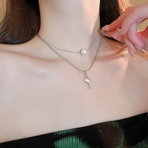 Detail of silver double-layered necklace with white pearl and zircon butterfly pendant