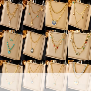 Detail of layered gold necklaces with butterfly, snake, and evil eye pendants