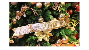 Dettaglio del nastro natalizio color champagne con testo e decorazioni a sfera festive