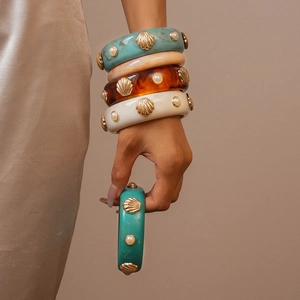 Bracelets en résine avec coquillages dorés et perles sur fond de soie chaleureux