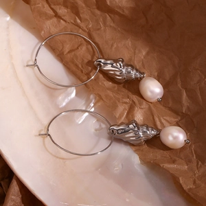 Detailed shot of silver conch shell and white pearl charms on large hoop earrings