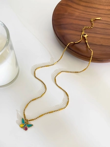 Detailed close-up of golden necklace featuring colorful enamel butterfly pendants and unique bead chain