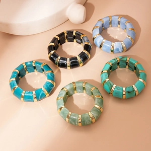 Detail of colorful resin bangles with marble texture and gold metal spacers