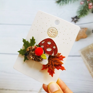 Close-up of handmade autumn hair clips featuring glittery hedgehog and mushroom motifs