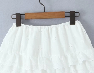 Détail d'une mini-jupe blanche avec des volants superposés et de la broderie délicate