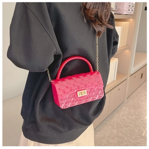 Close-up of pink quilted jelly bag featuring a gold clasp and red beaded handle strap