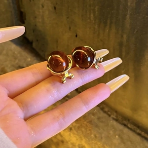 Vintage amber resin drop earrings in gold setting held by hand against textured wall