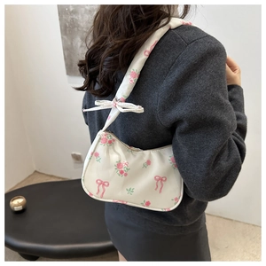 Close-up of crescent underarm bag with pink rose and bow prints on white fabric