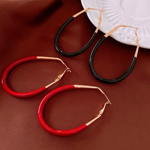 Détail de boucles d'oreilles ovales en émail rouge et noir avec touches de métal doré