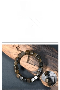 Macro detail of dark brown square wood beads with gold spacer accents on a bark backdrop
