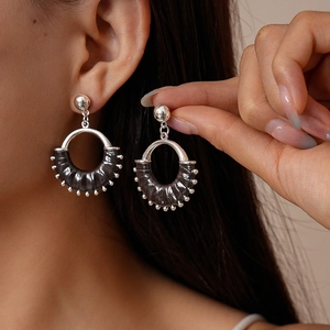 Close-up of retro hollow geometric hoop earrings with leather wrap and beaded edge
