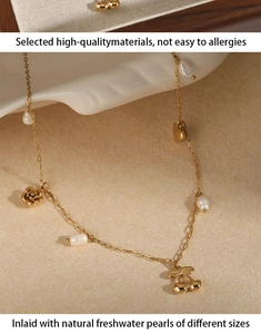 Détail d'un collier doré avec perles d'eau douce naturelles et pendentifs cerise et fleurs