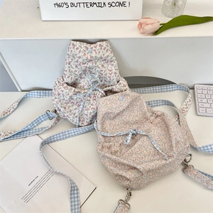 Detail view of floral canvas backpack with drawstring closure and blue checkered straps