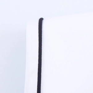 Detailed view of high-quality white woven fabric with contrasting black piping trim edges