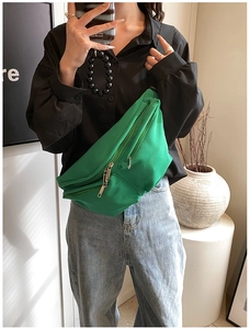 Close-up of green nylon crossbody bag with multi-zipper pockets and adjustable strap