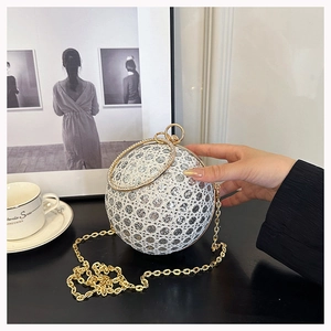 Close-up of spherical evening bag with sparkling rhinestones and golden ring handle