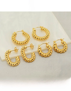 Detailed view of gold plated titanium steel twisted rope hoop earrings on marble surface