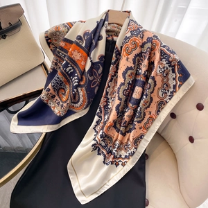 Navy blue and orange paisley silk-like square scarf draped over a black dress on a chair